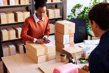 Black woman packing goods with colleague