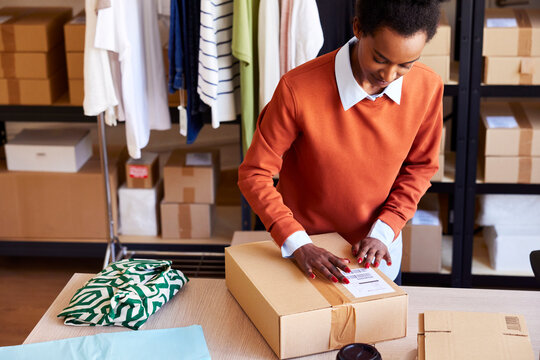 Black lady attaching sticker to carton box