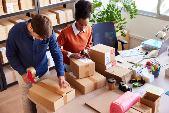 Multiracial coworkers preparing parcels for shipping
