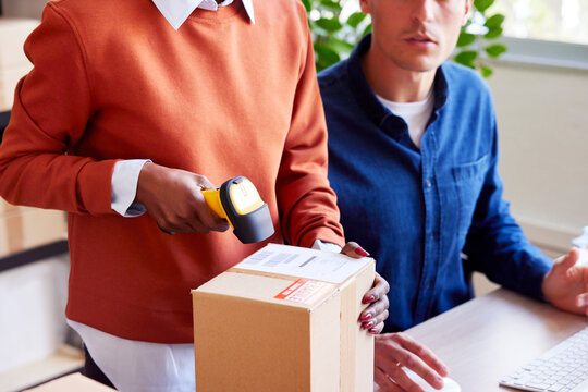 Logistic manager scanning barcode near colleague