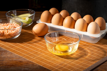 Multiple eggs and egg wash on wooden chopping board