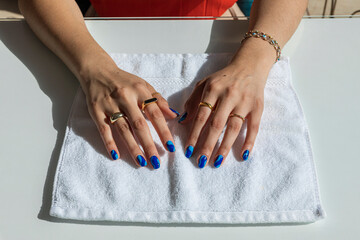 Woman's hands with gold rings and blue painted nails
