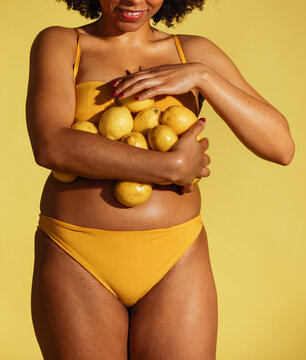 Black woman collecting lemons in arms