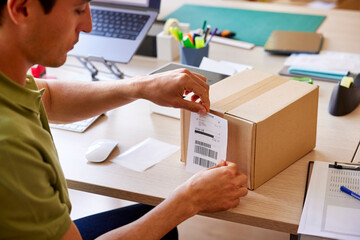 Post office worker attaching address paper to parcel