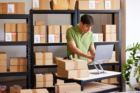 Logistic manager using laptop near shelves
