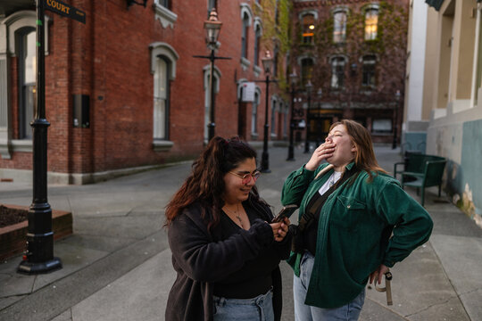 Two friends looking at phone together in city.