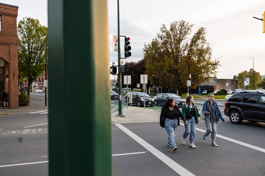 Three friends walking on crosswalk in city.