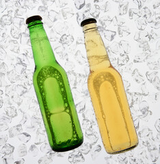 A green bottle of beer and a clear yellow bottle backlit on a bed of ice. The bottles have no labels. High Key.