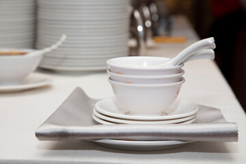 White tableware with serving spoons on table with back plates