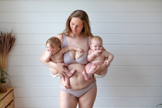 woman in lingerie posing holding two babies