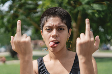 Rebellious young woman sticking out her tongue and middle fingers.