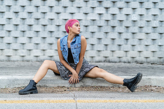 Young woman sitting at the edge of the sidewalk.