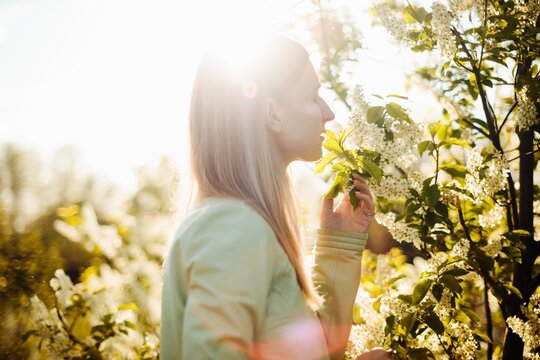 Young female smelling flowers on tree - Springtime