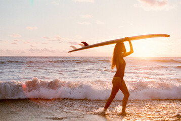 woman on black sand beach with her surfboard