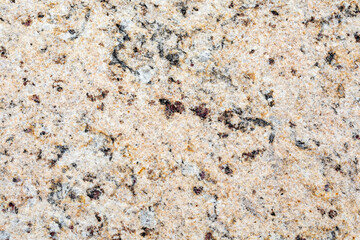 The texture of natural granite stone. The background of pinkish-beige stone interspersed with yellow, brown, gray and black tones.