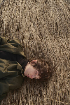Androgynous woman lying on dry grass and crying