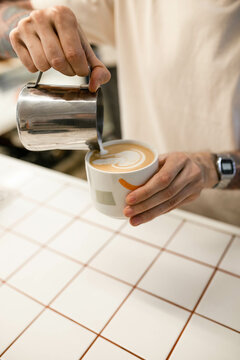 Close-up barista's hand making latte coffee pouring milk 