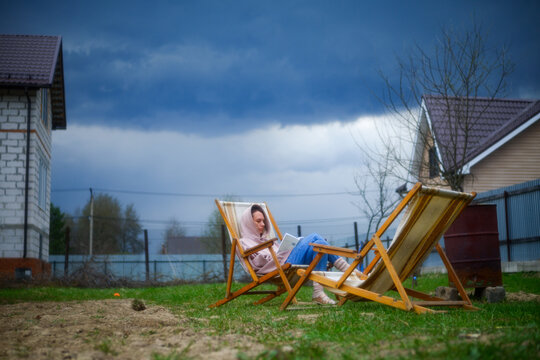 Woman Resting With Book On Summer Lounger