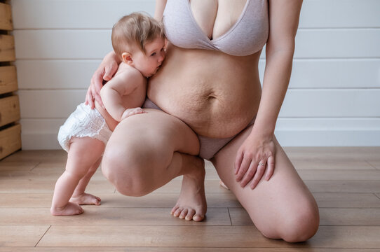 infant kisses mother stretch marks belly
