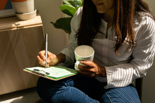 Woman writing on clipboard sitting on the office floor