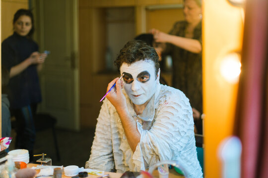 An actor  in front of a mirror makes make-up himself