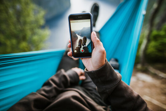 Man resting in hammock and taking photo of his legs
