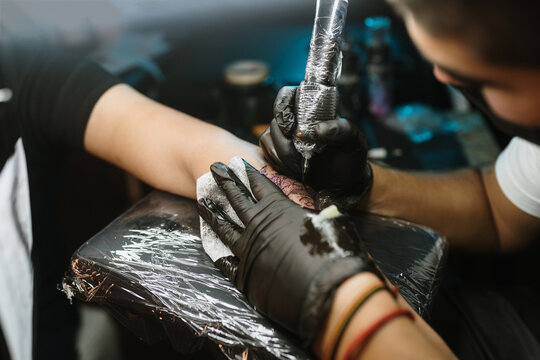 Close-up of tattoer using tattoo machine on an arm
