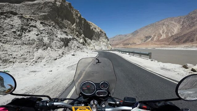 POV Motorcyclist riding motorbike by scenic mountain road in Himalayas. Biker on motorcycle going between mountain valley by landscape path. Steering wheel view. Moto trip