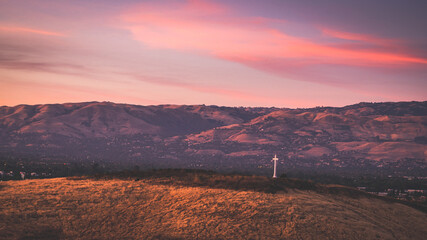 sunset over cross on the mountains