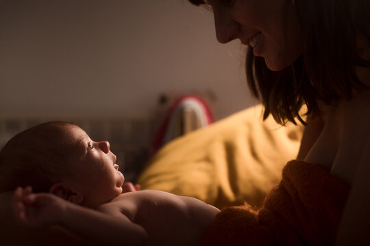 Smiling newborn and mother looking to each other