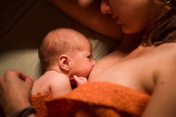 Intimate newborn portrait breastfeeding on bed 