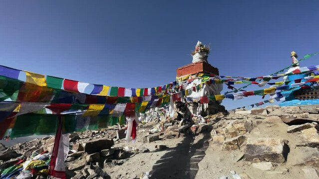 Buddhist flags flutter in the wind on a high pass in the Himalayas among beautiful mountains