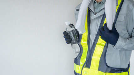 プラスチックボトルを持つ作業服の男性｜建設業の熱中症対策イメージ