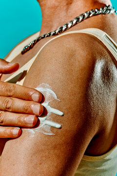 man in a tank top applies some sunblock to his arm