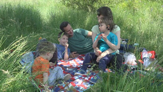Big family of parents with three kids picnic in nature