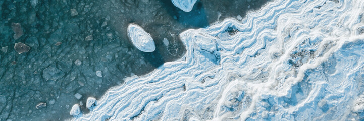 Top view of the icy seashore. Winter aerial photograph of the sea coast. Ice floes in freezing sea...