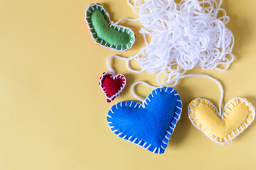 Abstract background a ball of white threads with colored hearts on a yellow background.
