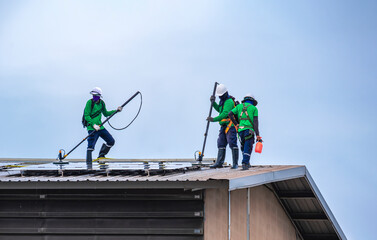 Group of professional cleaning service workers clean the solar panels on industrial building roof...