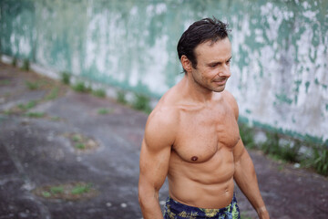Portrait of a sportive strong man standing in a old tennis court