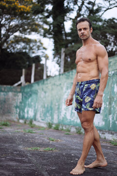 A middle-aged man with a muscular body walks around a sport field