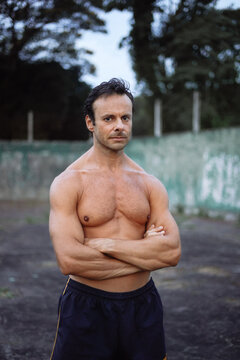 Portrait of a sportive strong man standing in a old tennis court