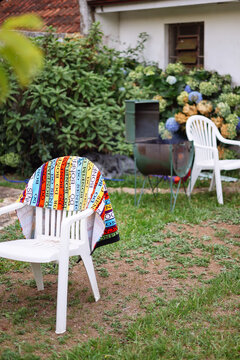 Two white chairs in the garden with a colourful towel over it