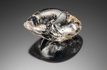 Transparent quartz with mineral inclusions on a gray background