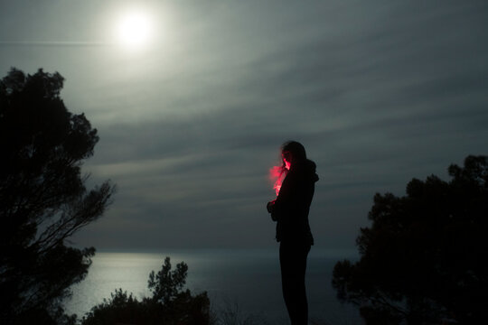 Woman with red light under the moonlight 