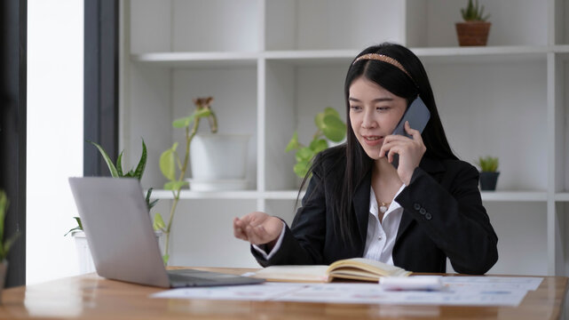 Asian businesswoman talking on the phone with customer in the office.