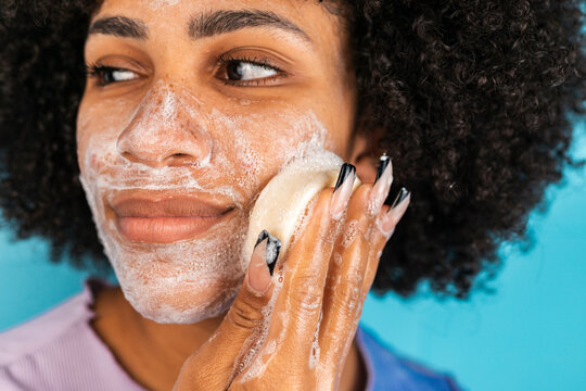Hispanic woman cleansing face with handmade soap
