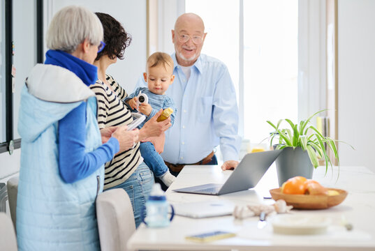 Grandparents, mother with baby talking at home.