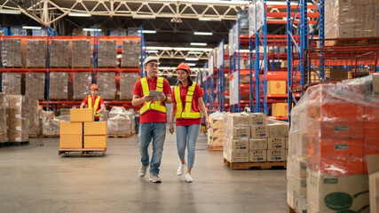 Male and female warehouse workers Working at a distribution center, standing, talking, at a large warehouse. New arrivals of additional items in the warehouse department. Employees who organize the di