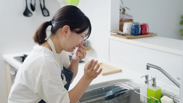 60p　キッチンが臭くて鼻をつまむ女性（家事・主婦）