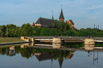 Fototapeta na wymiar View of the Koningberg Cathedral on Immanuel Kant Island against the background of the bridge over the Pregolya River on a sunny summer day, Kaliningrad, Russia
